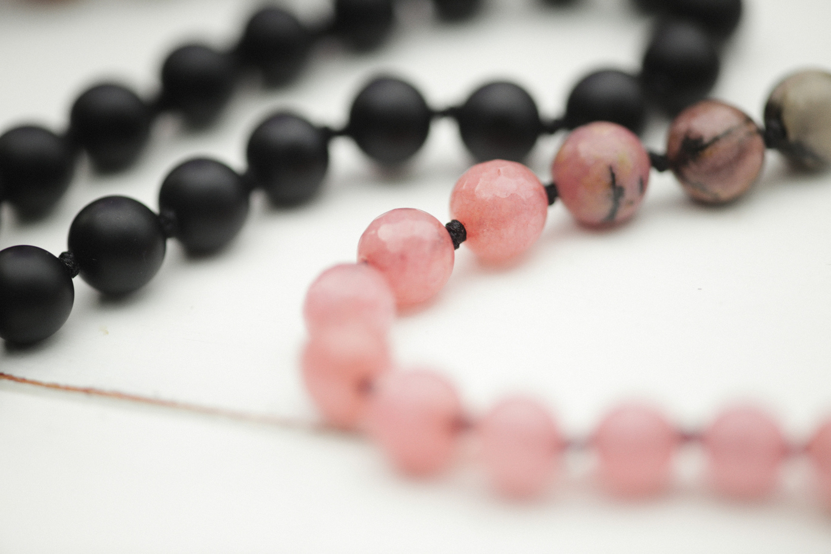Pink and Black Beaded Bracelets on White Surface